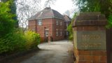 Red-brick exterior of Mond Court Apartments with a driveway and a brick gatepost reading Mond Court