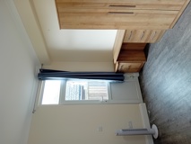 Bedroom at Eynesbury House with an oak chest of drawers and a window with navy curtains
