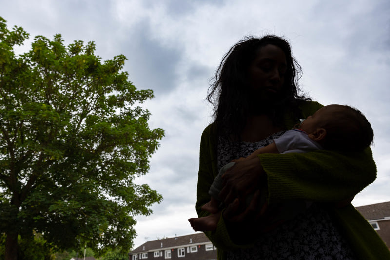 Parent cradling a baby outdoors against a cloudy sky at Clairmont family assessment centre