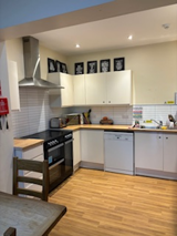 Kitchen at Greenview House with cream units, a black range cooker, extractor hood and dishwasher