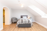 Loft bedroom at Brynawel with a single bed, a tartan throw, an armchair and a skylight