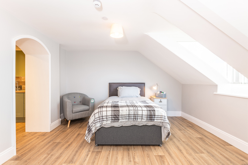 Loft bedroom at Brynawel with a single bed, a tartan throw, an armchair and a skylight