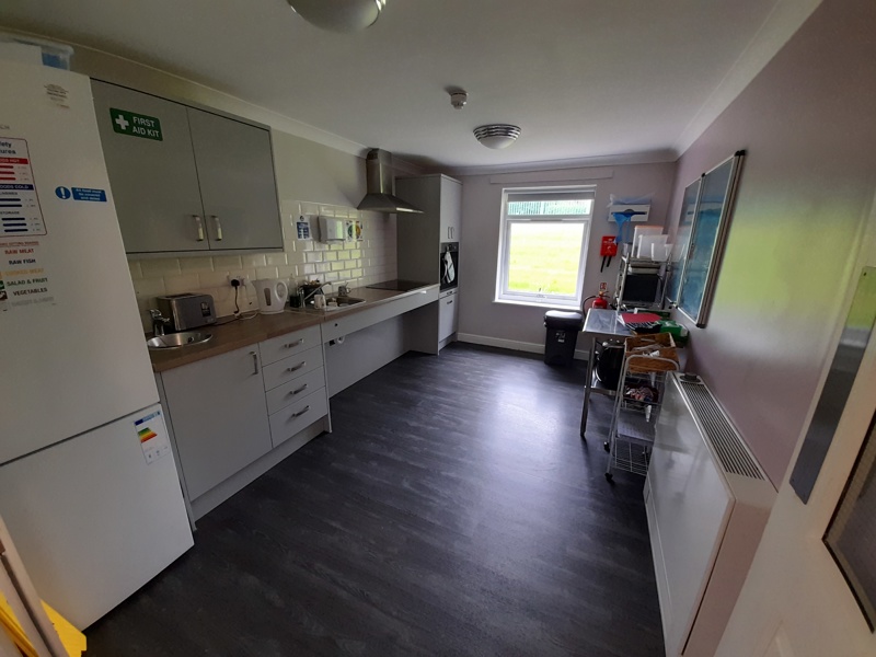 Kitchen at Boston House with white units, a toaster and kettle and a window overlooking the garden