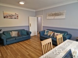 Lounge at Hazeldene with two blue sofas, a patterned dining table and framed coastal prints