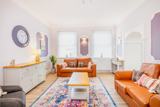 Lounge at Brynawel with tan leather sofas, a patterned rug, a large wall clock and lilac wall panels
