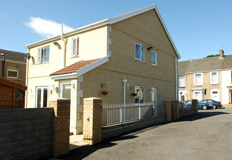 Front exterior of Bakelyn Lodge, a pebbledashed detached house with a tiled porch and a railed brick forecourt