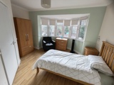 Bedroom at Evergreen with a double bed, oak furniture and a bay window over a green feature wall