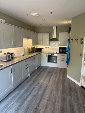 Kitchen at Manor Lodge with grey units, sage-green walls and a wood-effect floor