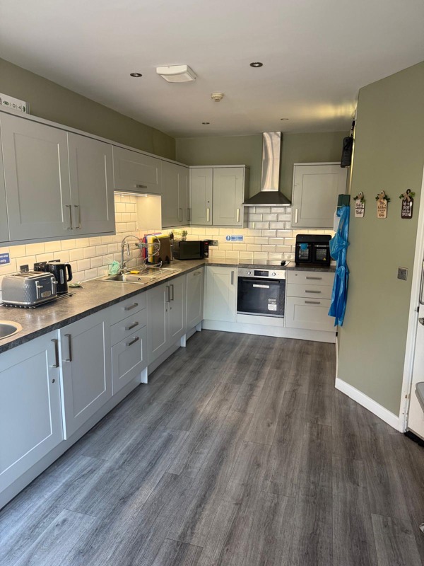 Kitchen at Manor Lodge with grey units, sage-green walls and a wood-effect floor