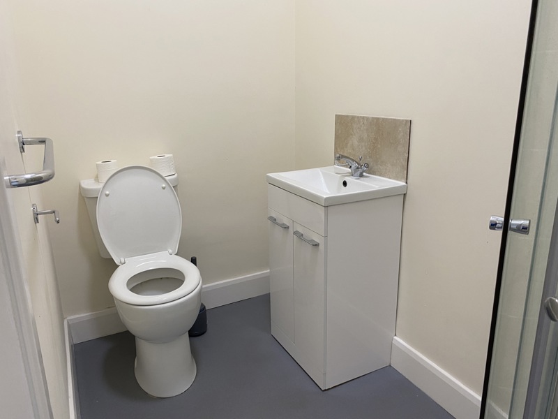Bathroom at Cranwell Court with a toilet, vanity basin, grab rail and shower cubicle