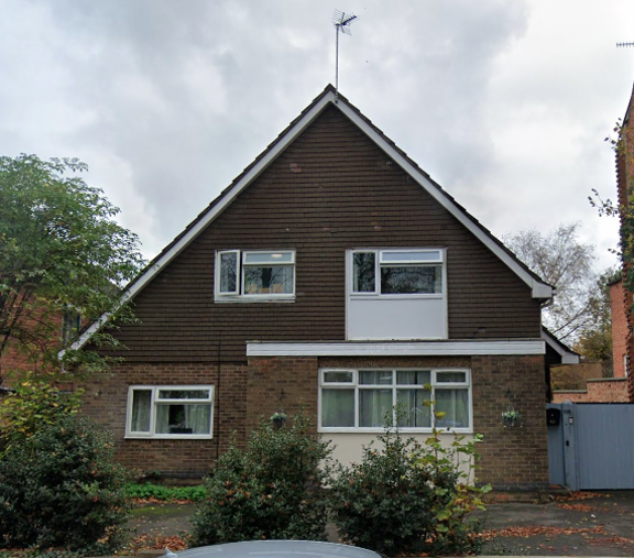 Exterior of St Georges, a detached house with a tile-hung gable, brick lower storey and shrubs by the entrance