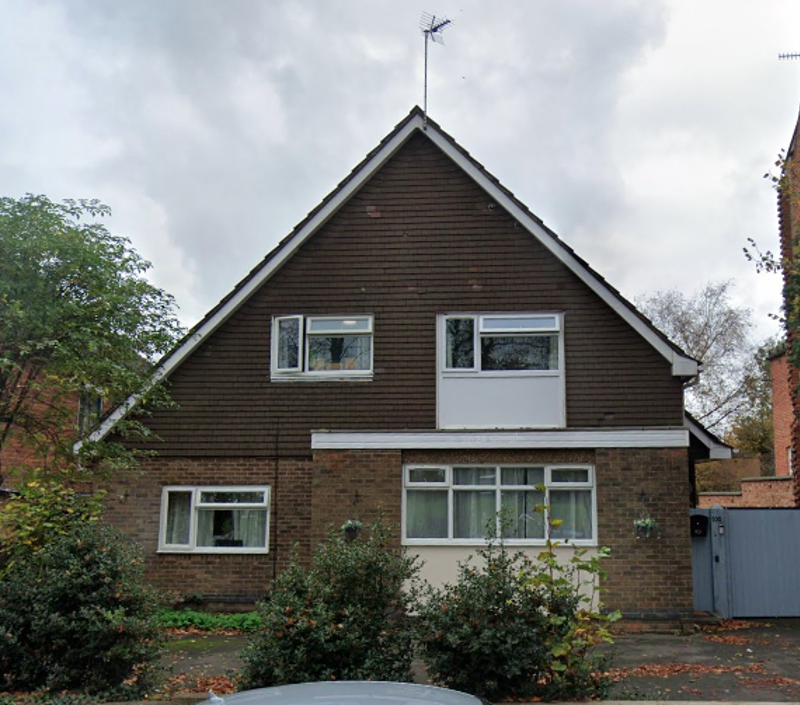 Exterior of St Georges, a detached house with a tile-hung gable, brick lower storey and shrubs by the entrance