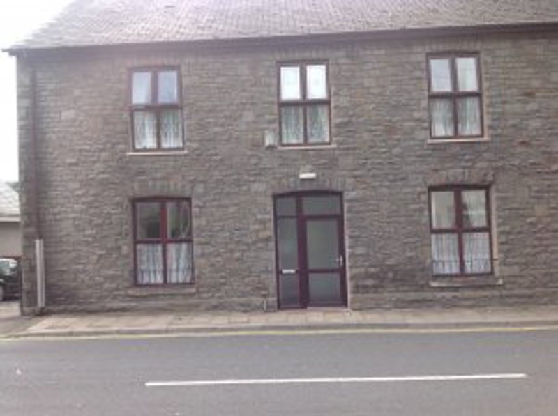Exterior of Ty Gobaith, a grey stone two-storey building with white-framed windows and a central door on a roadside