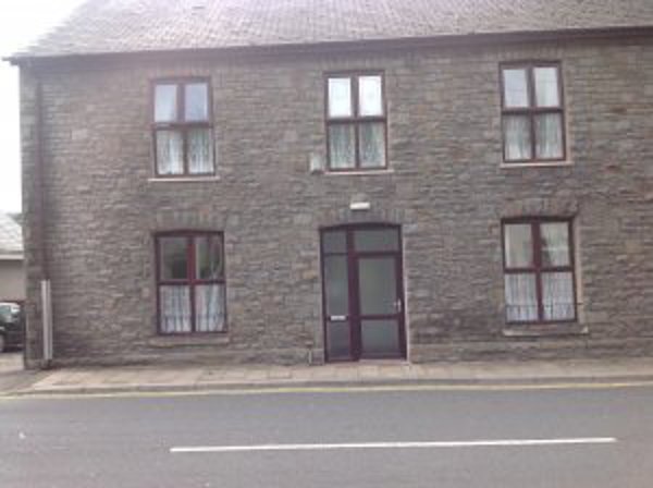 Exterior of Ty Gobaith, a grey stone two-storey building with white-framed windows and a central door on a roadside