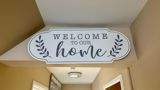 Welcome to our home wooden sign mounted above a hallway entrance at Pinetrees