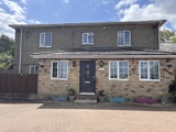 Brick front exterior of Manor Farm with a black front door, white windows and a paved driveway