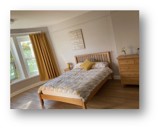 Bedroom at Manor Lodge with a double bed, mustard curtains and wooden furniture