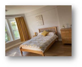 Bedroom at Manor Lodge with a double bed, mustard curtains and wooden furniture