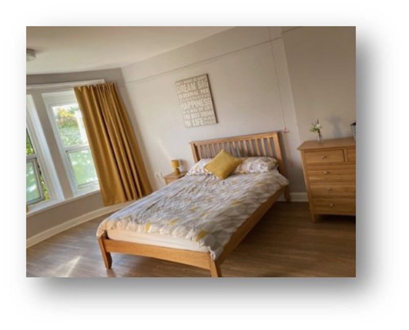 Bedroom at Manor Lodge with a double bed, mustard curtains and wooden furniture