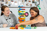 Two women playing a giant wooden block tower game at a table at Eilat