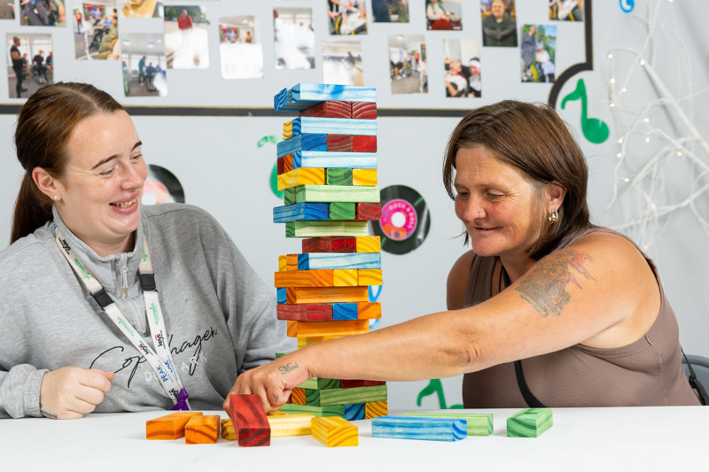 Two women playing a giant wooden block tower game at a table at Eilat