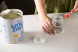 Hands measuring a scoop of infant formula into a bottle at Crown House family assessment centre
