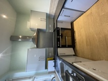 Kitchen at Kemble House with white gloss units, a stainless steel extractor hood and black oven