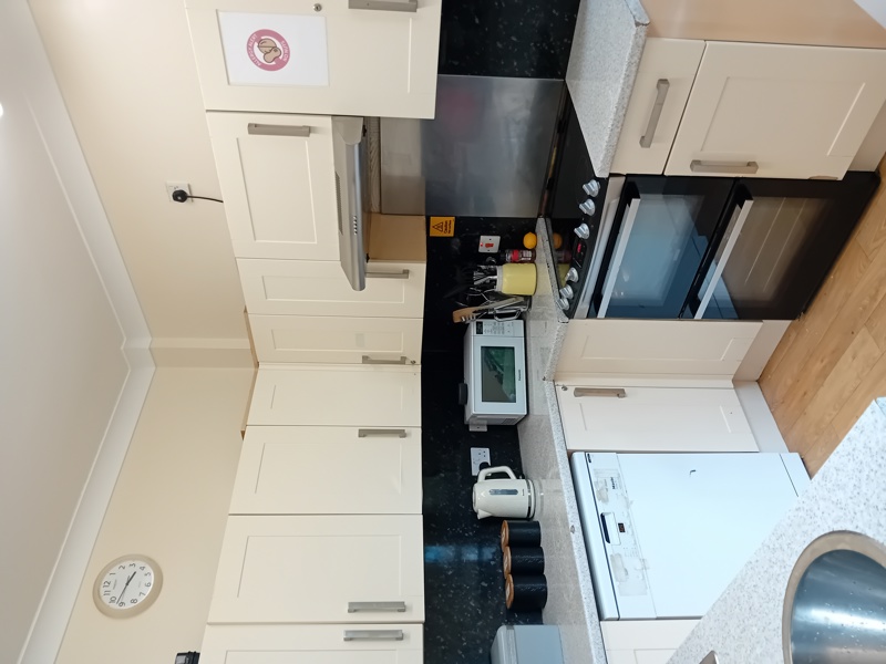 Kitchen at Eynesbury House with cream shaker units, black granite worktops and an oven and microwave