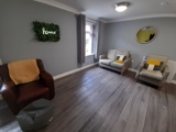 Lounge at Boston House with leather and fabric armchairs and a green 'home' ivy wall sign