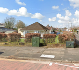 Street view of Dyfan Court, a single-storey bungalow with a hipped roof behind a hedge and railings
