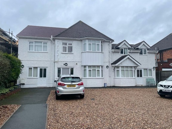 Front exterior of Greenview House, a white rendered detached house with bay windows and a gravel drive