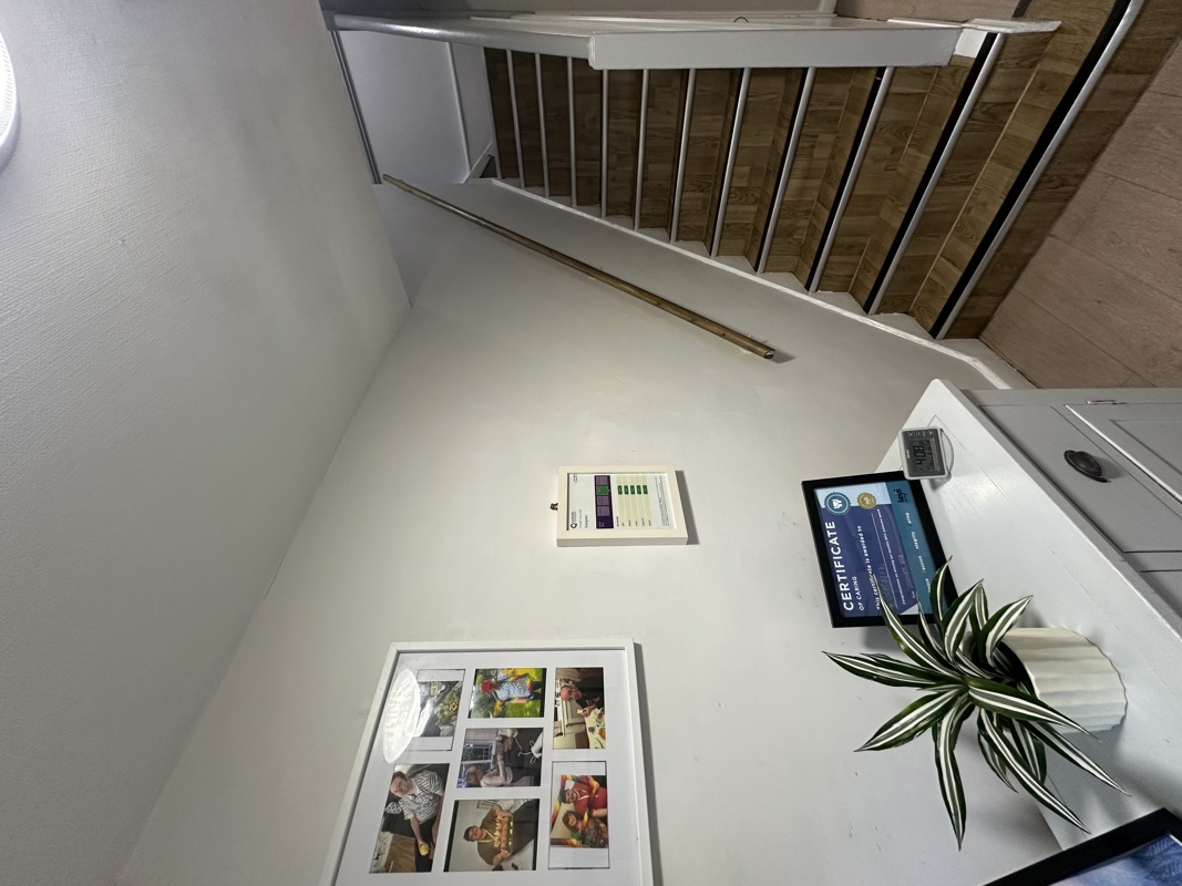 Hallway and staircase at Evergreen with framed resident photo displays and a certificate of caring on the wall