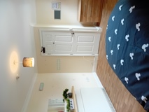 Bedroom at Eynesbury House with patterned navy bedding, a bedside lamp and wood-effect flooring