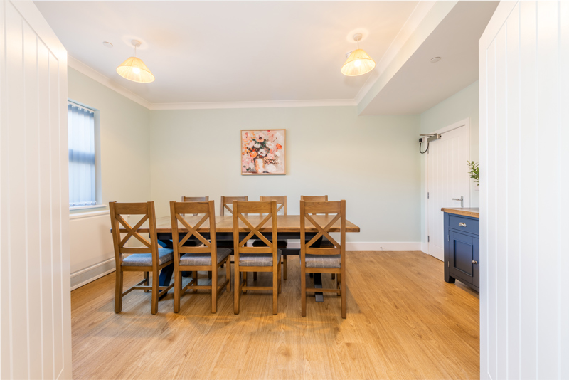 Dining room at Church Road with a wooden table and chairs and sage green walls