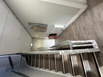Staircase and landing at Glanmore with a painted bannister, framed artwork and wood-effect flooring