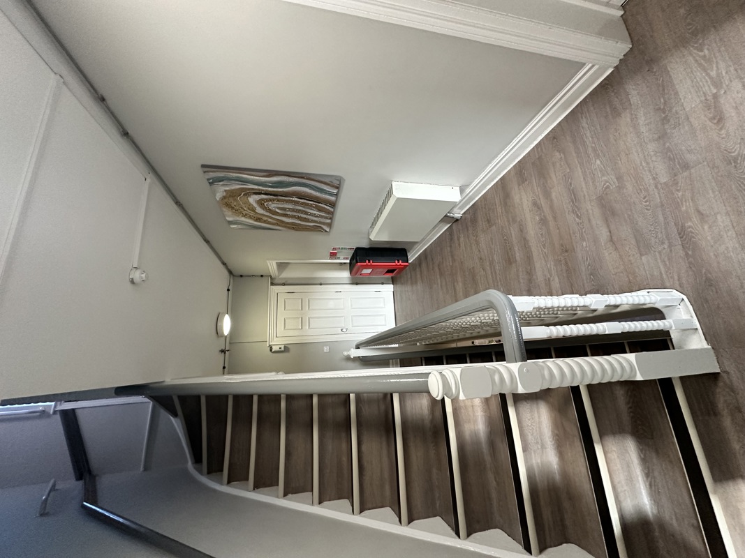 Staircase and landing at Glanmore with a painted bannister, framed artwork and wood-effect flooring