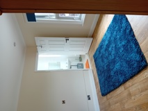 Bedroom with en-suite at Eynesbury House showing a blue rug and a tiled bathroom through the open door