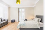 Spacious bedroom at Brynawel with a grey upholstered bed, a sofa and French doors to a balcony