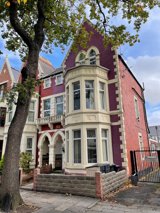 Front exterior of Princes Court, a Victorian red-brick and cream house with a gabled bay window and arched porch