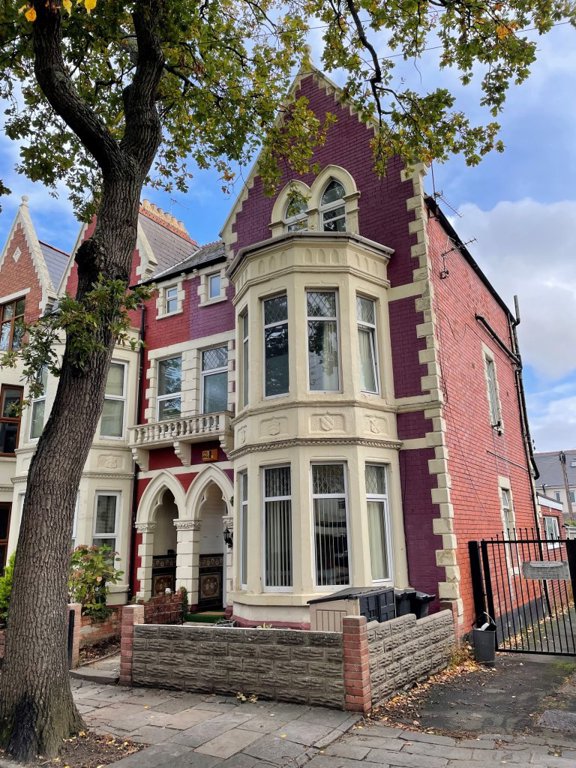 Front exterior of Princes Court, a Victorian red-brick and cream house with a gabled bay window and arched porch