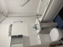 Accessible bathroom at Glanmore with a toilet, basin, grab rails and white tiled walls