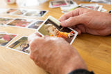 Hands looking through printed family photos on a wooden table at Victoria Villas family assessment centre