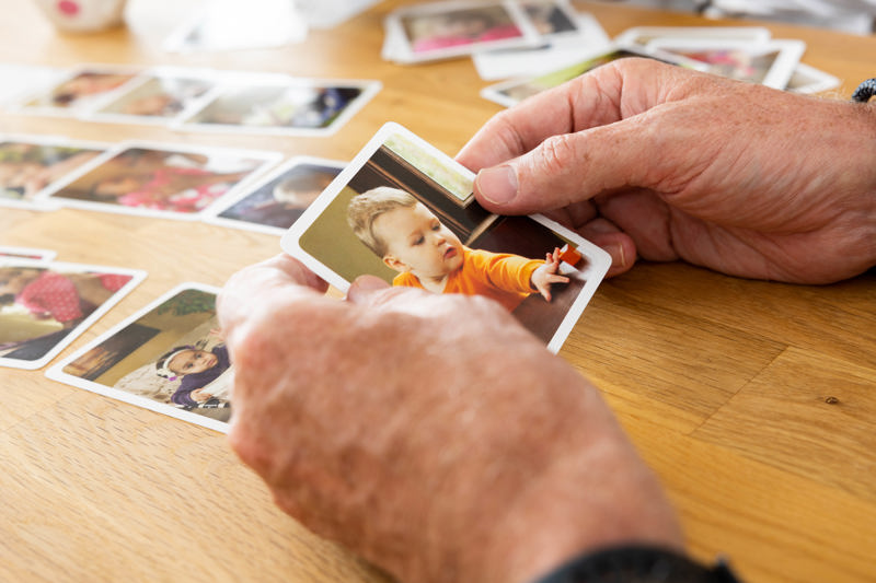 Hands looking through printed family photos on a wooden table at Victoria Villas family assessment centre