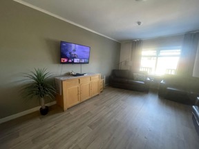 Living room at Rosewood with a wall-mounted TV, a wooden sideboard and dark leather sofas