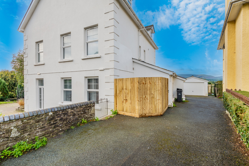 Side view of Brynawel, a white-rendered detached house with a driveway, garage and mountains beyond