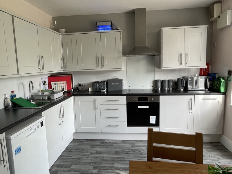 Communal kitchen at Birchwood House with white cabinets, black worktops and integrated appliances