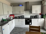 Communal kitchen at Birchwood House with white cabinets, black worktops and integrated appliances