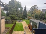 Back garden at Manor Lodge with a lawn, paved patio, seating and mature trees