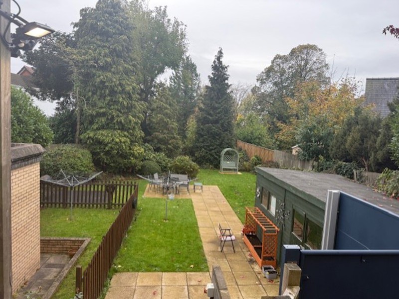 Back garden at Manor Lodge with a lawn, paved patio, seating and mature trees
