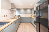Kitchen at Bayview Lodge with grey shaker units, wood-effect worktops and an American-style fridge freezer
